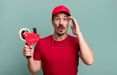 Photo for Adult man looking happy, astonished and surprised. deliveryman packer concept - Royalty Free Image