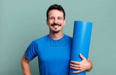 Téléchargez les photos : Homme adulte souriant heureux avec une main sur la hanche et confiant. concept de fitness et yoga - en image libre de droit