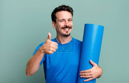 Téléchargez les photos : Homme adulte se sentant fier, souriant positivement avec les pouces levés. concept de fitness et yoga - en image libre de droit