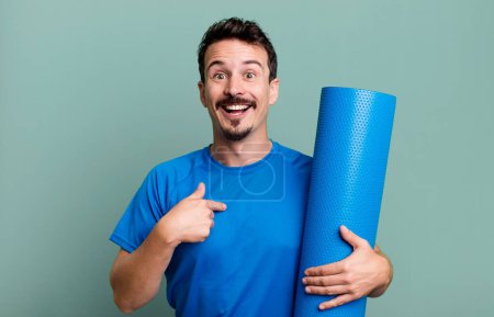 Téléchargez les photos : Homme adulte se sentant heureux et pointant vers soi-même avec un excité. concept de fitness et yoga - en image libre de droit