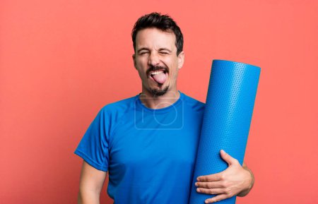 Photo for Adult man with cheerful and rebellious attitude, joking and sticking tongue out. fitness and yoga concept - Royalty Free Image