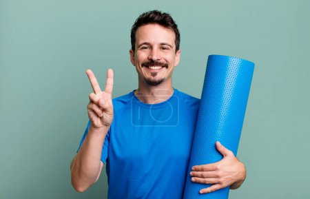Photo for Adult man smiling and looking friendly, showing number two. fitness and yoga concept - Royalty Free Image