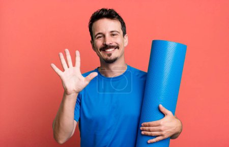 Téléchargez les photos : Homme adulte souriant et regardant amical, montrant le numéro cinq. concept de fitness et yoga - en image libre de droit