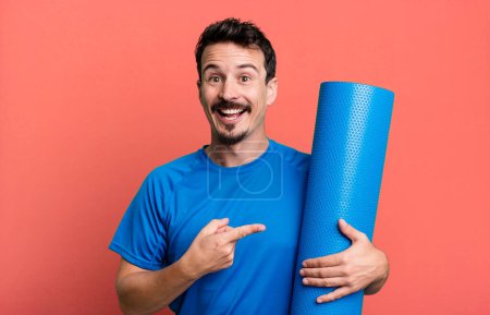 Téléchargez les photos : Homme adulte regardant excité et surpris pointant vers le côté. concept de fitness et yoga - en image libre de droit