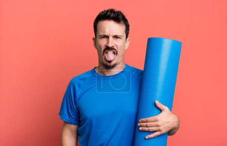 Foto de Hombre adulto sintiéndose disgustado e irritado y la lengua hacia fuera. concepto de fitness y yoga - Imagen libre de derechos