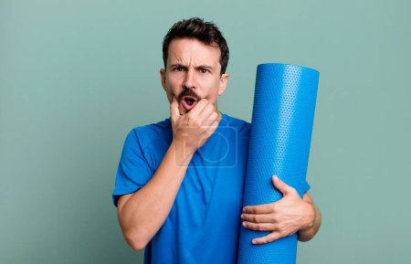 Photo pour Homme adulte avec la bouche et les yeux grands ouverts et la main sur le menton. concept de fitness et yoga - image libre de droit