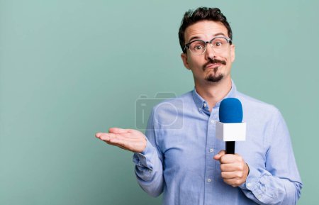 Photo for Adult man feeling puzzled and confused and doubting with a microphone. presenter or journalist concept - Royalty Free Image