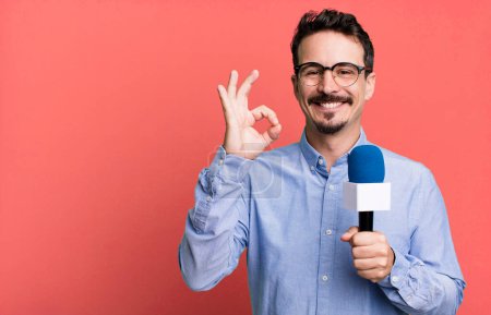 Photo for Adult man feeling happy, showing approval with okay gesture with a microphone. presenter or journalist concept - Royalty Free Image