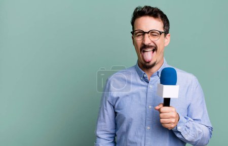 Foto de Adult man with cheerful and rebellious attitude, joking and sticking tongue out with a microphone. presenter or journalist concept - Imagen libre de derechos