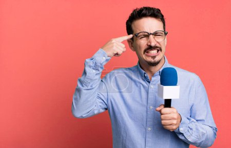 Foto de Adult man feeling confused and puzzled, showing you are insane with a microphone. presenter or journalist concept - Imagen libre de derechos