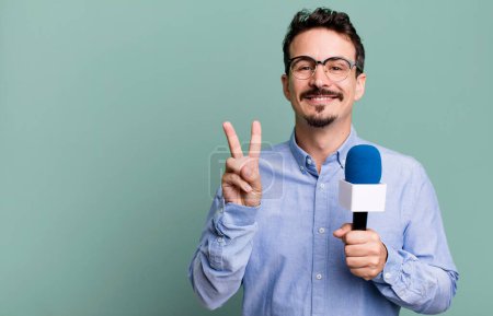 Foto de Adult man smiling and looking friendly, showing number two with a microphone. presenter or journalist concept - Imagen libre de derechos