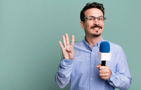 Téléchargez les photos : Adult man smiling and looking friendly, showing number four with a microphone. presenter or journalist concept - en image libre de droit