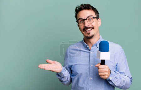 Téléchargez les photos : Adult man smiling cheerfully, feeling happy and showing a concept with a microphone. presenter or journalist concept - en image libre de droit
