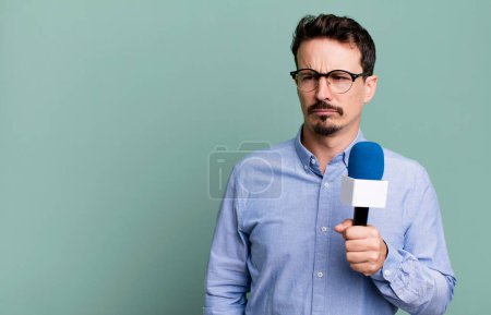 Foto de Adult man feeling sad, upset or angry and looking to the side with a microphone. presenter or journalist concept - Imagen libre de derechos