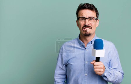 Foto de Adult man looking puzzled and confused with a microphone. presenter or journalist concept - Imagen libre de derechos