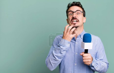 Photo for Adult man looking desperate, frustrated and stressed with a microphone. presenter or journalist concept - Royalty Free Image