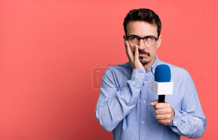 Foto de Adult man feeling bored, frustrated and sleepy after a tiresome with a microphone. presenter or journalist concept - Imagen libre de derechos