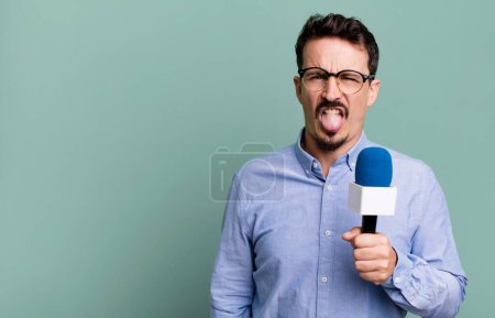 Foto de Adult man feeling disgusted and irritated and tongue out with a microphone. presenter or journalist concept - Imagen libre de derechos