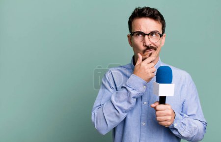 Foto de Adult man thinking, feeling doubtful and confused with a microphone. presenter or journalist concept - Imagen libre de derechos