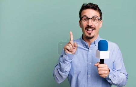 Foto de Adult man feeling like a happy and excited genius after realizing an idea with a microphone. presenter or journalist concept - Imagen libre de derechos