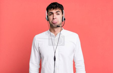 Foto de Hombre adulto sintiéndose triste y quejoso con una mirada infeliz y llorando con auriculares. concepto de operador de telemarketer - Imagen libre de derechos