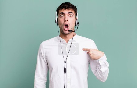 Photo for Adult man looking shocked and surprised with mouth wide open, pointing to self with headset. telemarketer operator concept - Royalty Free Image