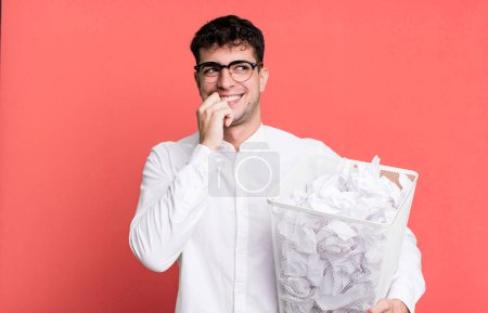 Foto de Hombre adulto sonriendo con una expresión feliz y segura con la mano en la barbilla. bolas de papel errores basura - Imagen libre de derechos