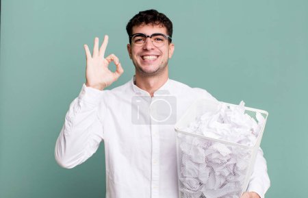 Photo for Adult man feeling happy, showing approval with okay gesture. paper balls mistakes trash - Royalty Free Image