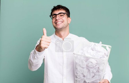 Photo for Adult man feeling proud,smiling positively with thumbs up. paper balls mistakes trash - Royalty Free Image