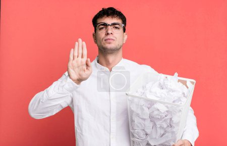 Photo for Adult man looking serious showing open palm making stop gesture. paper balls mistakes trash - Royalty Free Image