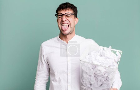 Photo for Adult man with cheerful and rebellious attitude, joking and sticking tongue out. paper balls mistakes trash - Royalty Free Image