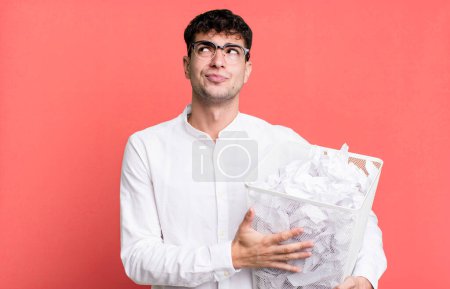 Téléchargez les photos : Homme adulte haussant les épaules, se sentant confus et incertain. boules de papier erreurs poubelle - en image libre de droit