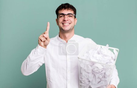 Photo for Adult man smiling and looking friendly, showing number one. paper balls mistakes trash - Royalty Free Image
