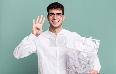 Photo for Adult man smiling and looking friendly, showing number four. paper balls mistakes trash - Royalty Free Image