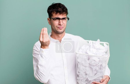 Téléchargez les photos : Homme adulte faisant un geste de capice ou d'argent, vous disant de payer. boules de papier erreurs poubelle - en image libre de droit