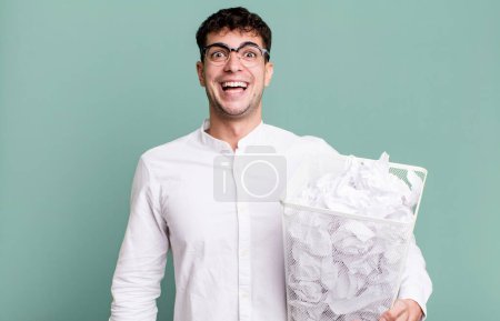 Photo for Adult man looking happy and pleasantly surprised. paper balls mistakes trash - Royalty Free Image