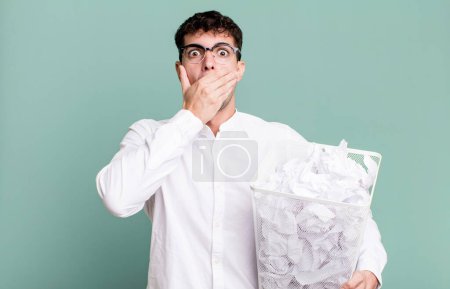 Téléchargez les photos : Homme adulte couvrant la bouche avec les mains avec un choc. boules de papier erreurs poubelle - en image libre de droit