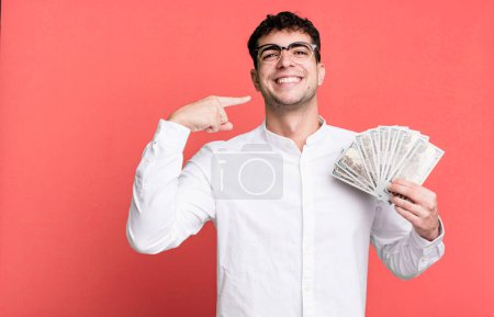 Foto de Hombre adulto sonriendo con confianza señalando a su propia sonrisa amplia. concepto de billetes en dólares - Imagen libre de derechos