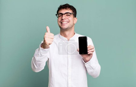 Photo for Adult man feeling proud,smiling positively with thumbs up and showing his smartphone screen - Royalty Free Image