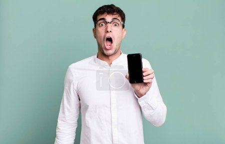 Téléchargez les photos : Homme adulte regardant très choqué ou surpris et montrant son écran de smartphone - en image libre de droit