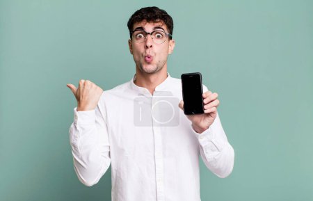 Foto de Hombre adulto mirando asombrado en incredulidad y mostrando la pantalla de su teléfono inteligente - Imagen libre de derechos