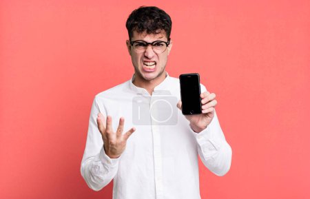Photo for Adult man looking angry, annoyed and frustrated and showing his smartphone screen - Royalty Free Image