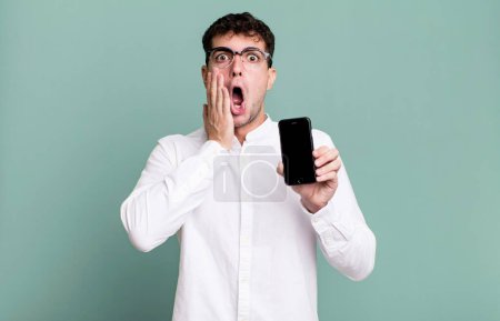 Foto de Hombre adulto se siente sorprendido y asustado y mostrando la pantalla de su teléfono inteligente - Imagen libre de derechos