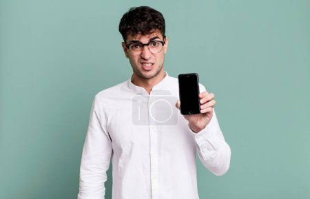 Foto de Hombre adulto se siente desconcertado y confundido y mostrando la pantalla de su teléfono inteligente - Imagen libre de derechos