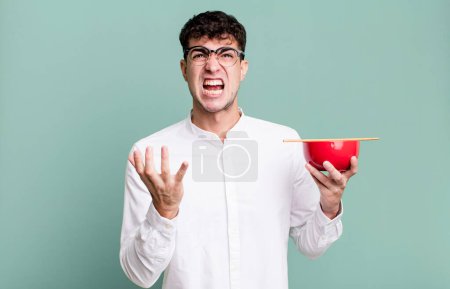Foto de Hombre adulto buscando desesperado, frustrado y estresado sosteniendo un tazón de fideos ramen - Imagen libre de derechos