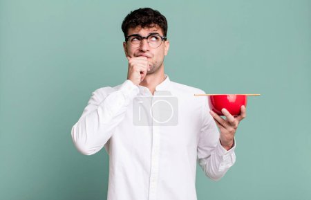 Photo for Adult man thinking, feeling doubtful and confused holding a ramen noodles bowl - Royalty Free Image