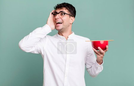 Téléchargez les photos : Homme adulte se sentant heureux, excité et surpris tenant un bol de nouilles ramen - en image libre de droit