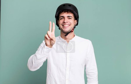 Foto de Hombre adulto sonriendo y mirando feliz, haciendo gestos de victoria o paz. ciudad concepto de motociclista - Imagen libre de derechos