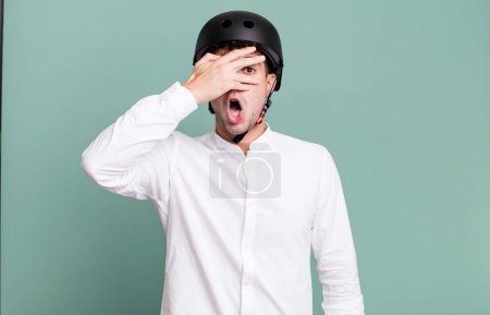 Foto de Hombre adulto que parece sorprendido, asustado o aterrorizado, cubriendo la cara con la mano. ciudad concepto de motociclista - Imagen libre de derechos