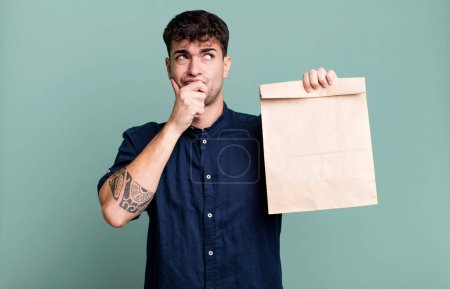 Photo for Adult man thinking, feeling doubtful and confused with a take away breakfast paper bag with a take away breakfast paper bag - Royalty Free Image